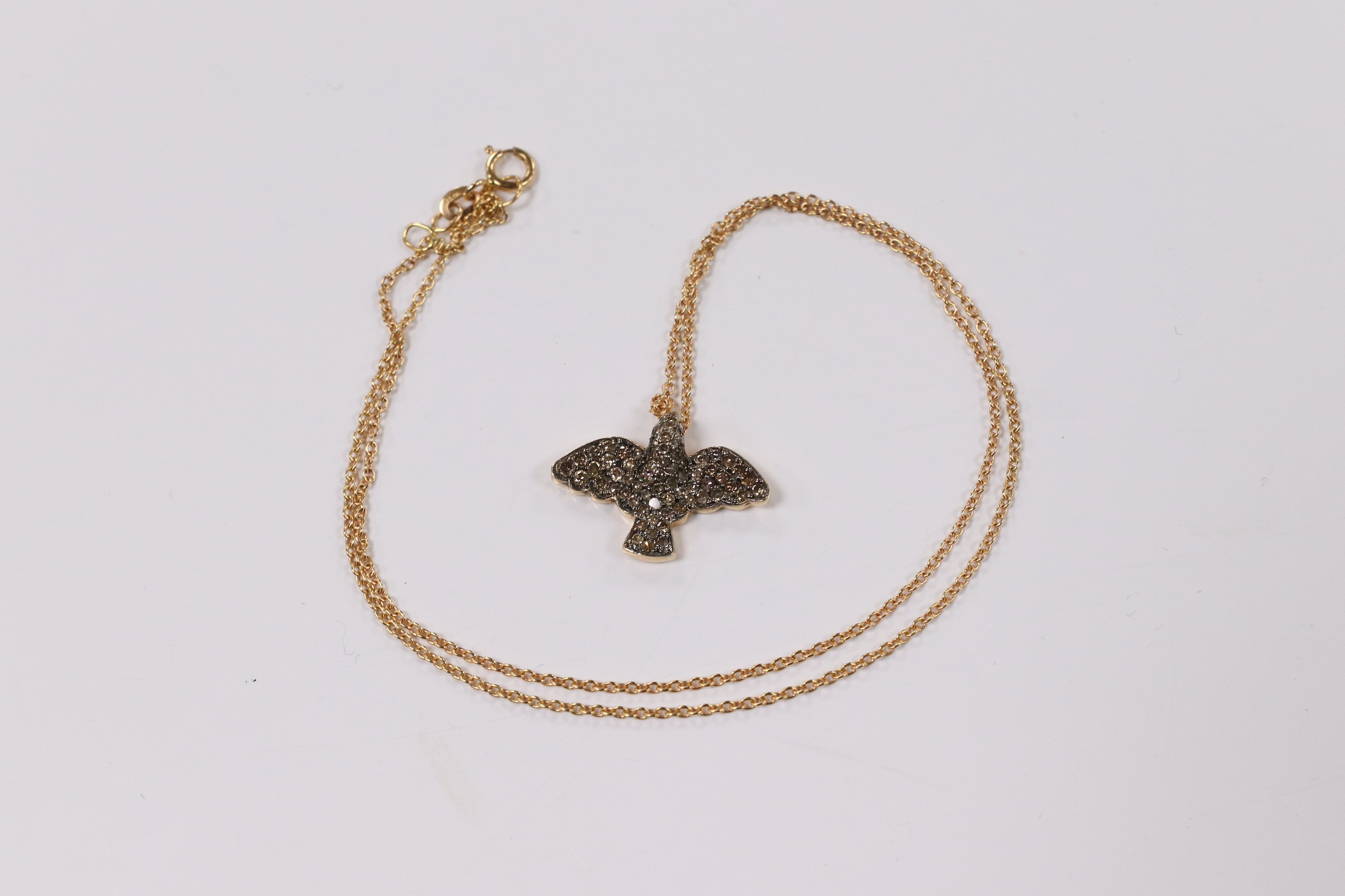 A modern 18k and pave set two colour diamond chip bird pendant, wing span 19mm, on an Italian 18k fine link chain, 36cm, gross weight 4.4 grams. Condition - fair to good